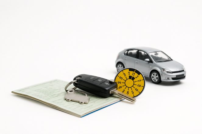 Fahrzeugschein, Autoschlüssel und abgelaufene TÜV-Plakette